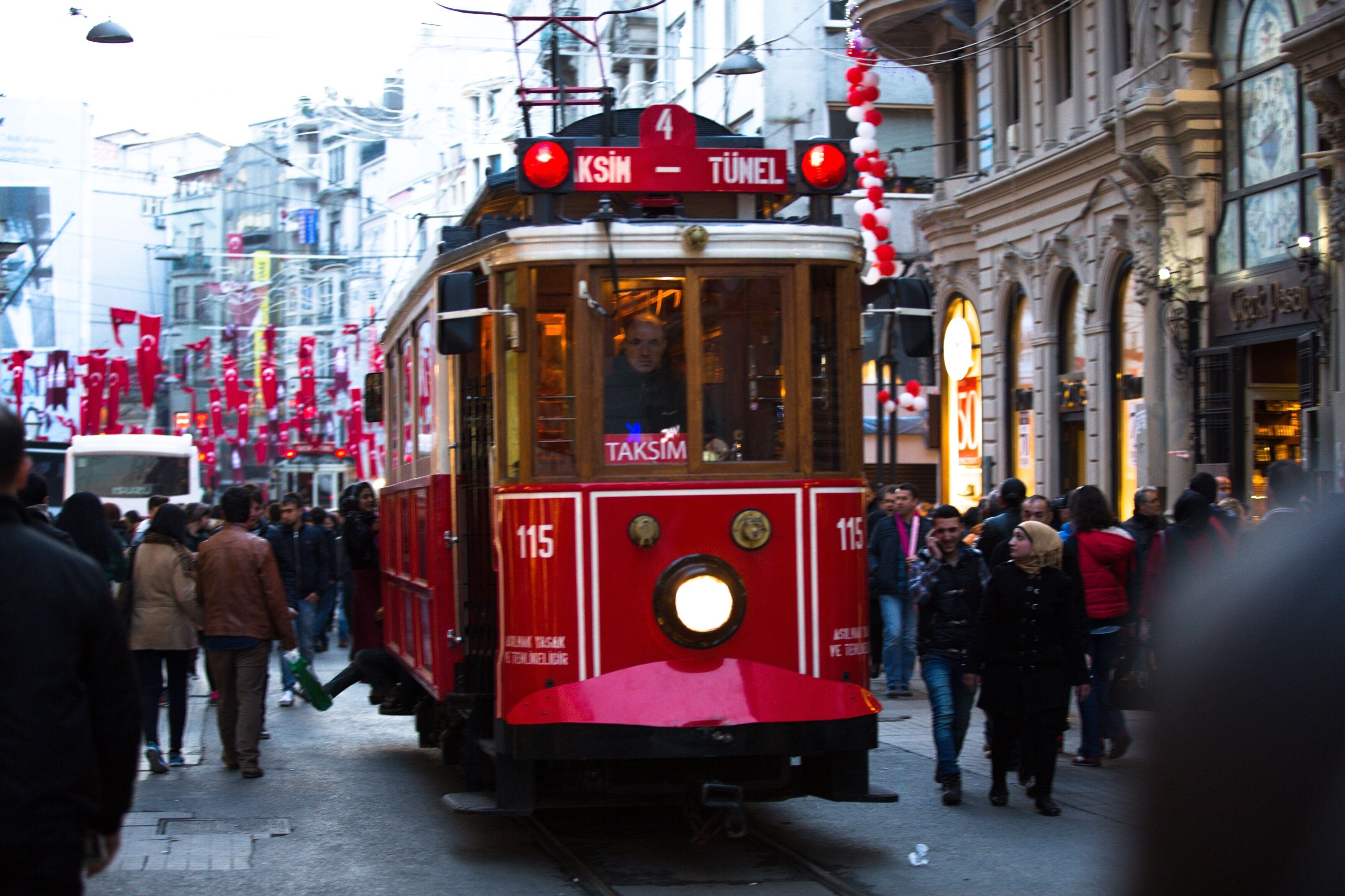Um elétrico vermelho com o número 115 numa rua movimentada.