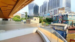 Uma varanda com vista para um horizonte urbano, incluindo edifícios modernos e uma grua de construção.