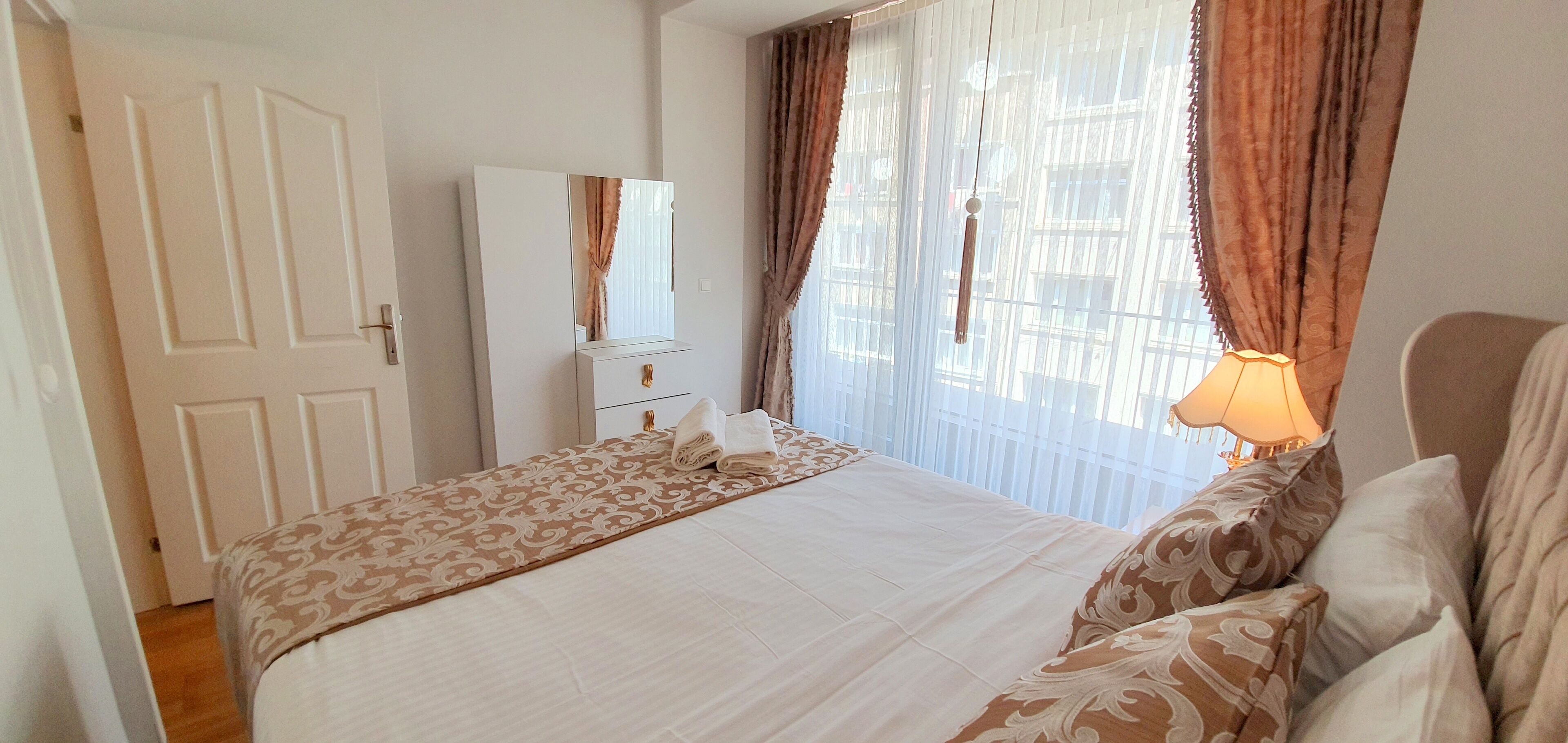 A bedroom with a bed, a wardrobe, and a window with curtains.