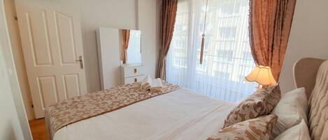 A bedroom with a bed, a wardrobe, and a window with curtains.