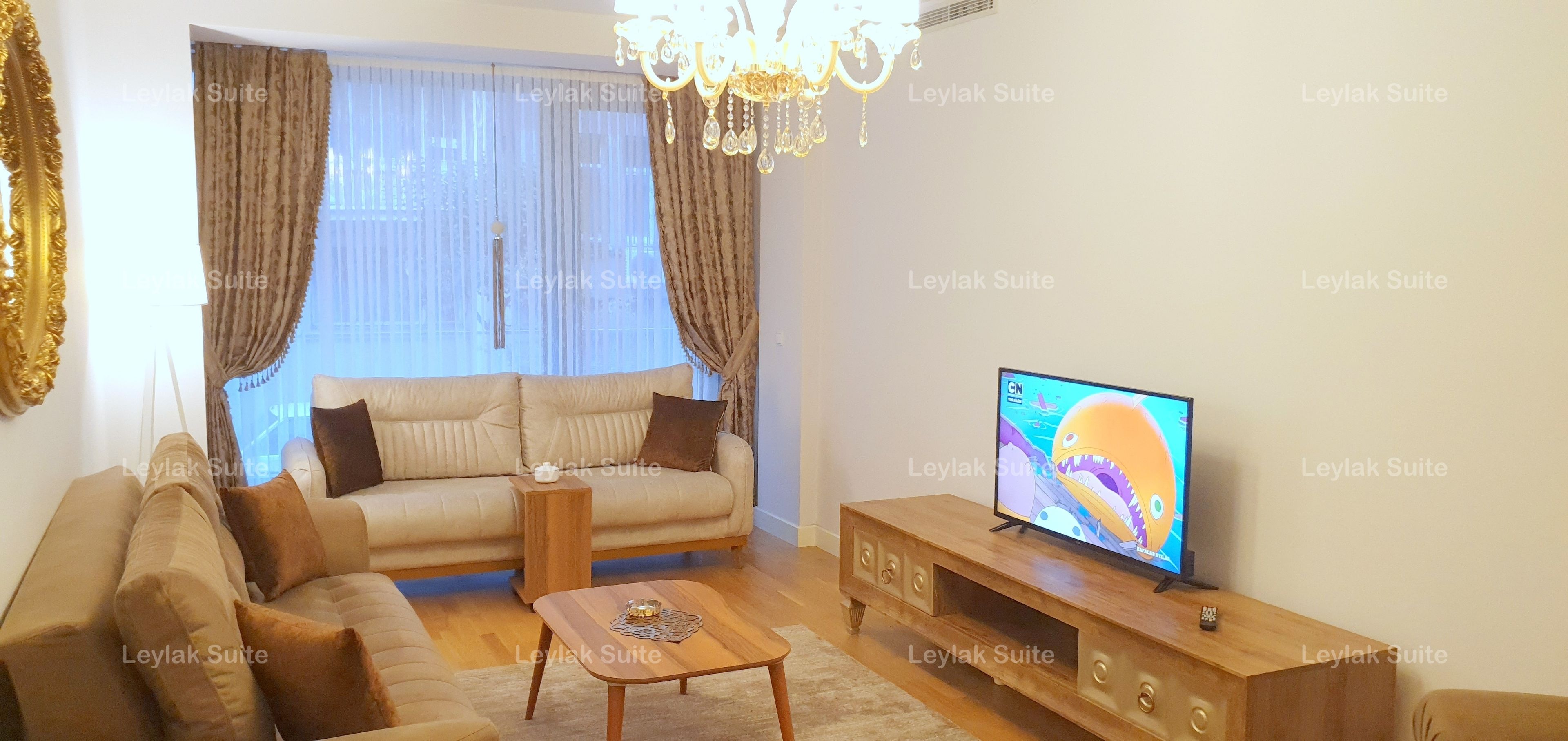 A living room with a sofa, coffee table, TV, and curtains.