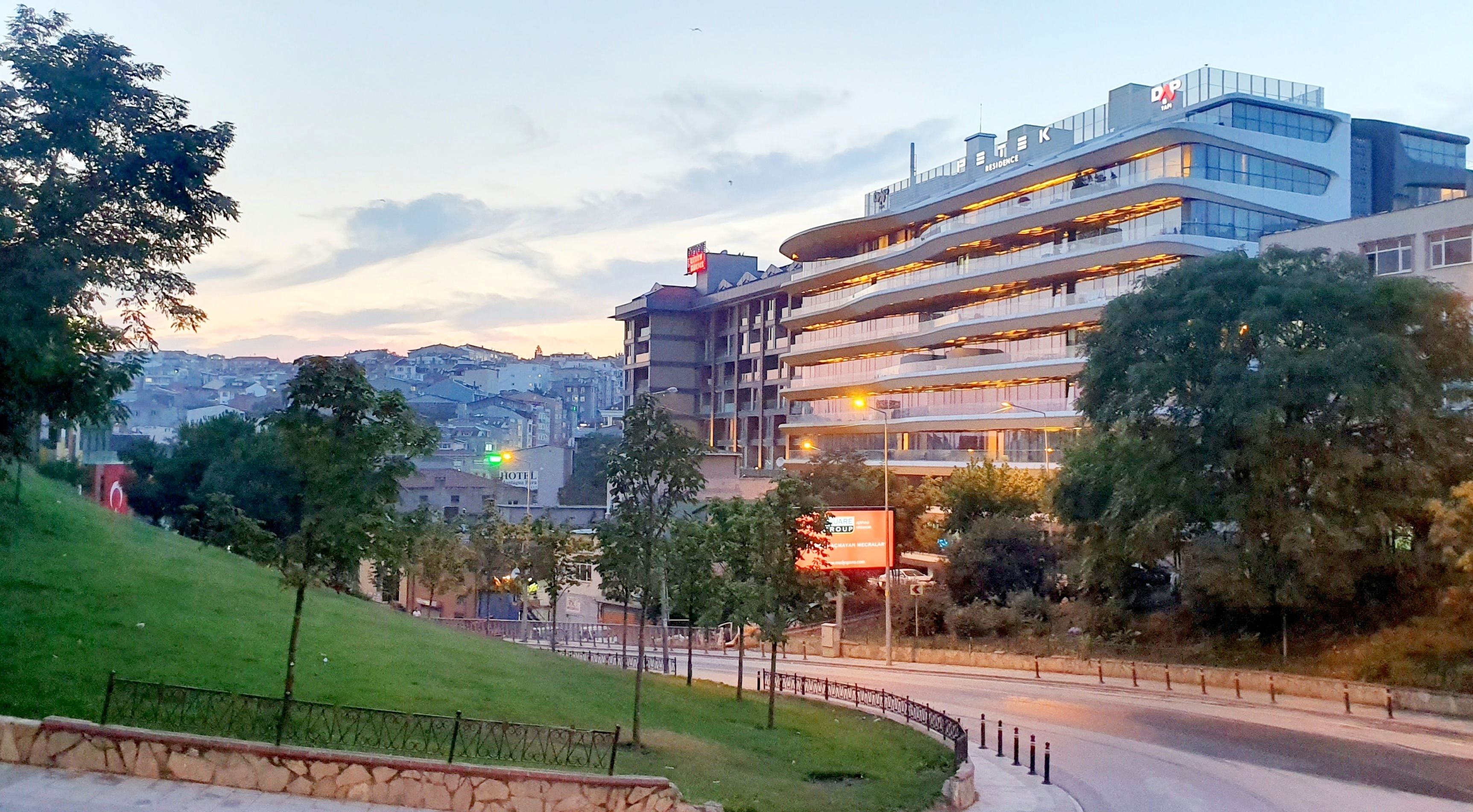 A modern hotel with multiple floors, a prominent sign for 'Hotel', and a view of the cityscape in the background.