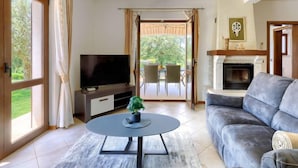 En stue med et fladskærms-tv, en sofa, et sofabord og en pejs.