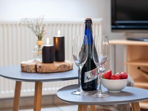 A table with a bottle of wine, two glasses, a candle, and a bowl of strawberries. - Apartment Juist by Interhome (Norddeich)