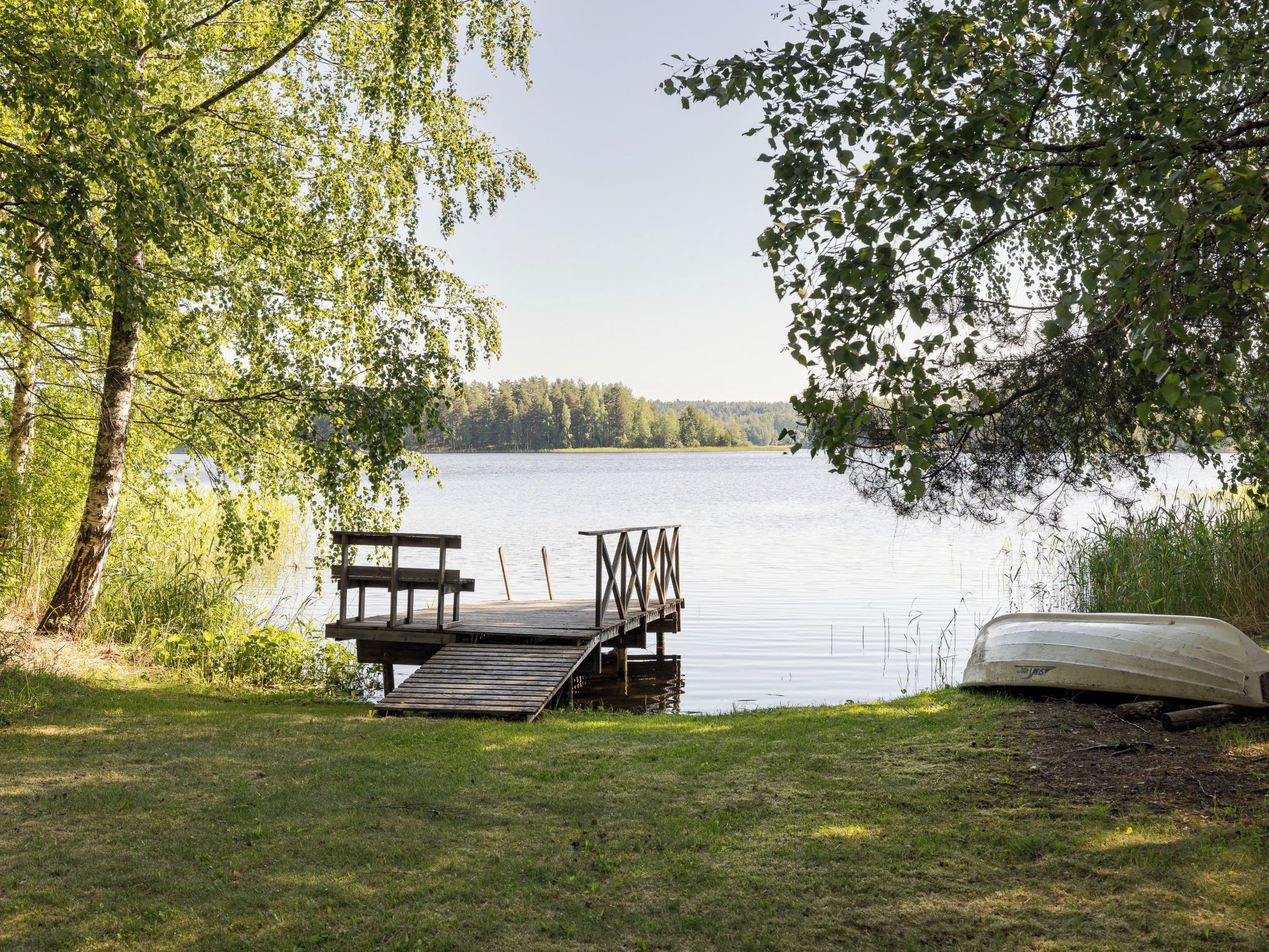 A lakeside dock with a bench and a canoe.
