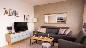 A modern living room with a grey sofa, a wooden coffee table, a TV, and a mirror on the wall. - Gezeiten by Interhome (Norddeich)