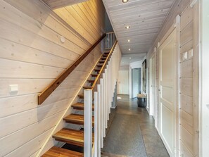 A wooden staircase with a handrail, leading to a landing with a door and a bench.