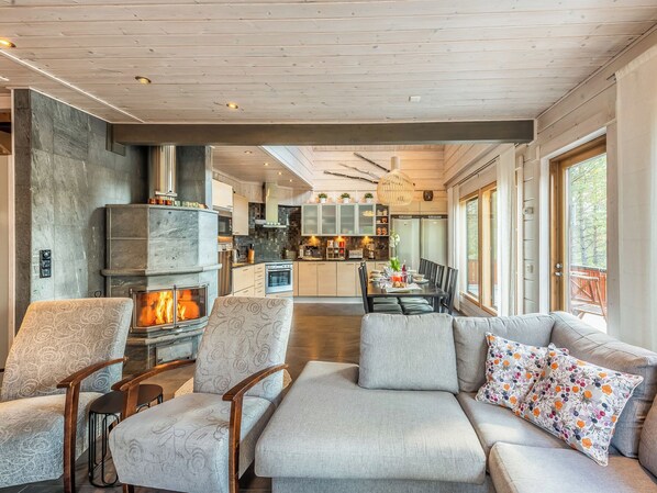 A modern living room with a fireplace, comfortable seating, and a view into the kitchen.