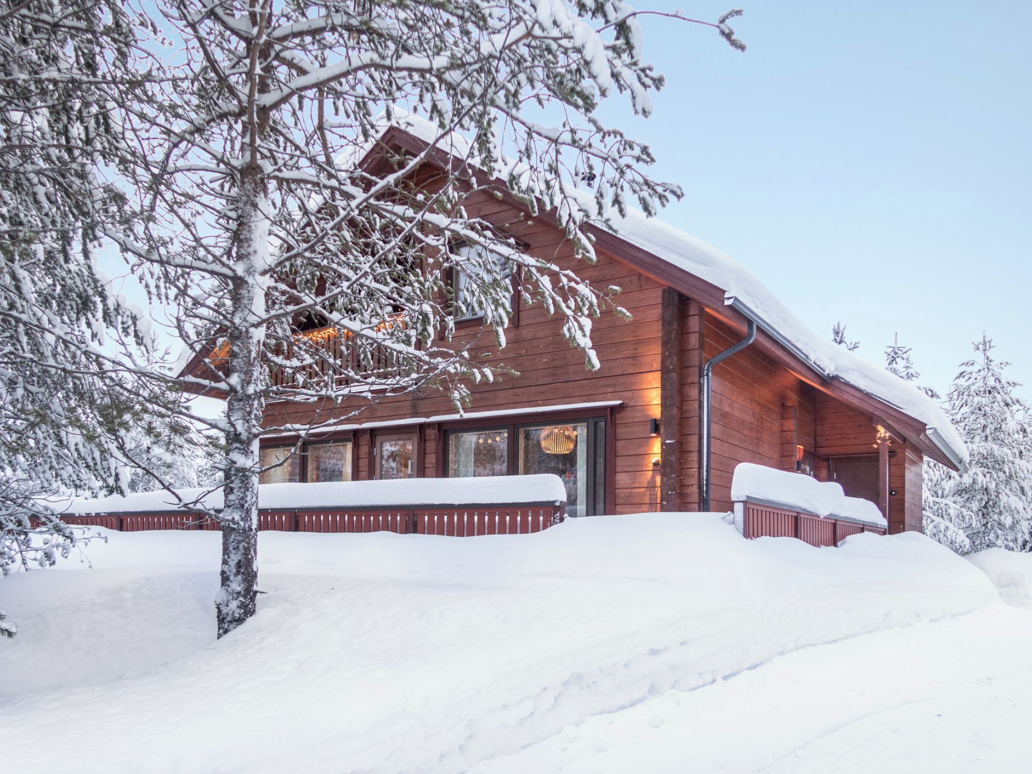 Una baita di legno con un'ampia finestra e un tetto imbiancato dalla neve.