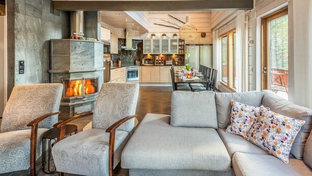 Een moderne woonkamer met een open haard, een eethoek en een keuken met grote ramen.