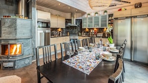 Een moderne keuken met een centraal eiland, roestvrijstalen apparatuur en een houtkachel.