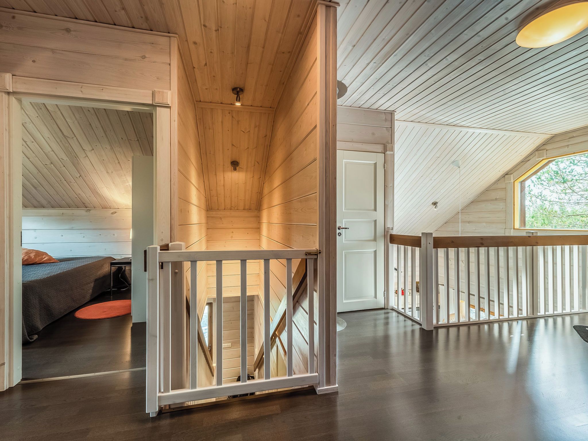 A spacious loft with a wooden interior, a staircase, and a large window providing natural light.