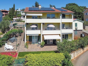 A multi-story building with balconies, outdoor seating, and a garden area.