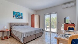 Un dormitorio con cama, armario, mesa con sillas y televisor.