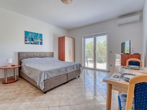 A bedroom with a bed, a wardrobe, a table with chairs, and a television.