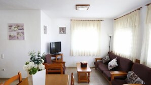 A living room with a TV, sofa, and dining table. - Vacation home Vicky by Interhome (Deltebre)