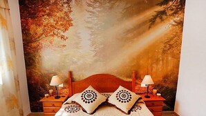 A bedroom with a large forest mural on the wall, a wooden bed with two pillows, two bedside tables with lamps, and a wooden dresser. - Vacation home Vicky by Interhome (Deltebre)