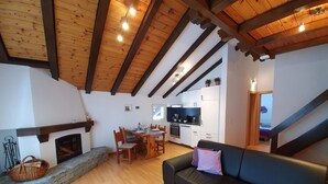 Uma sala de estar acolhedora com lareira, uma área de jantar e uma cozinha.
