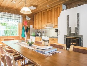 Une cuisine en bois dotée d’un îlot central, de meubles de rangement en bois et d’une cheminée en pierre.