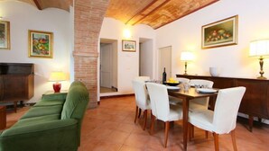 Un comedor con una mesa de madera, sillas blancas y una pared de ladrillo.