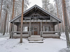A wooden cabin with a balcony, surrounded by snow-covered trees. - Kitkaranta by Interhome (Kuusamo)