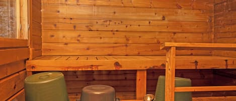 L’intérieur d’une cabane en bois, avec un lit superposé, une petite table et un récipient vert.