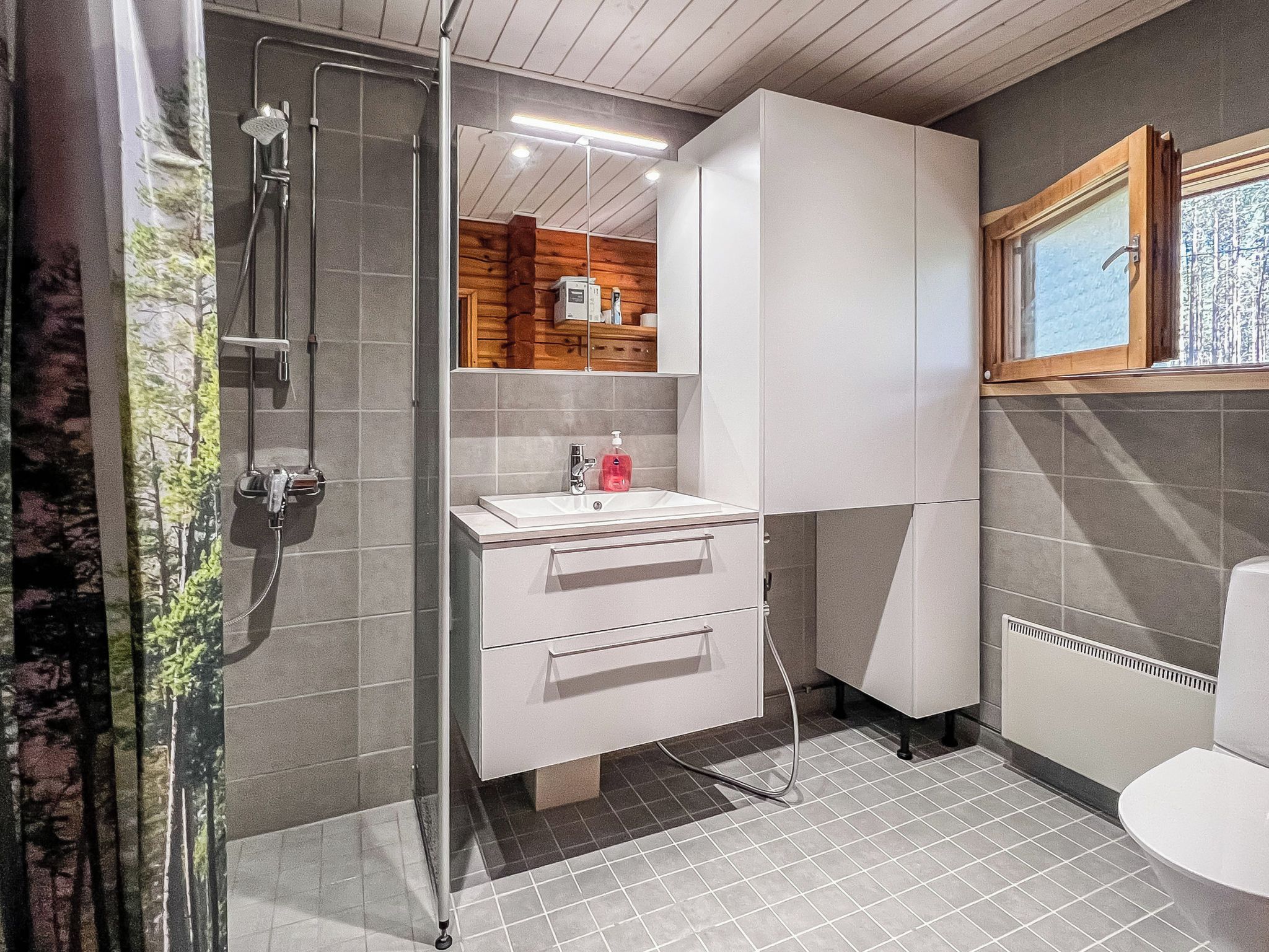 A modern bathroom with a shower, a sink with a mirror, and a toilet.