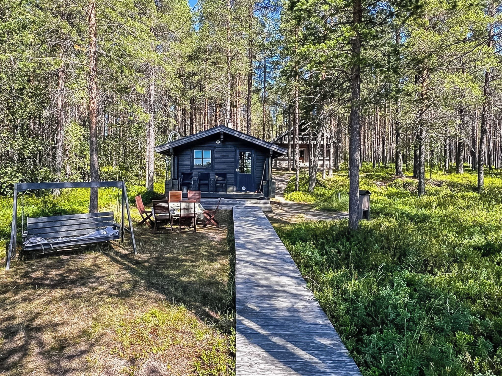 A cabin with a porch, a bench, and a table with chairs.
