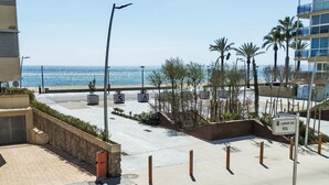 Eine Küstenstraße mit freiem Blick auf das Meer, Palmen und einem Gebäude mit der Aufschrift 'Carrer Del Sol'.