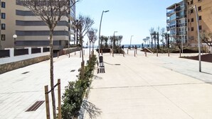 Ein modernes Stadtgebiet mit breitem Fußweg, Gebäuden mit Balkonen und blauem Himmel.