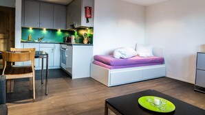 Un espacio habitable compacto con kitchenette, comedor y cama.