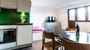 Cocina compacta con refrigerador, estufa y una mesa de comedor con sillas.