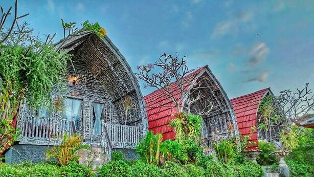 A row of traditional wooden houses with red roofs, surrounded by lush greenery. - Hotra Hill Cottage (Penida Island)