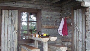 A rustic wooden cabin with a wooden bench and a table with a bowl of fruit. - Kultaranta by Interhome (Asikkala)