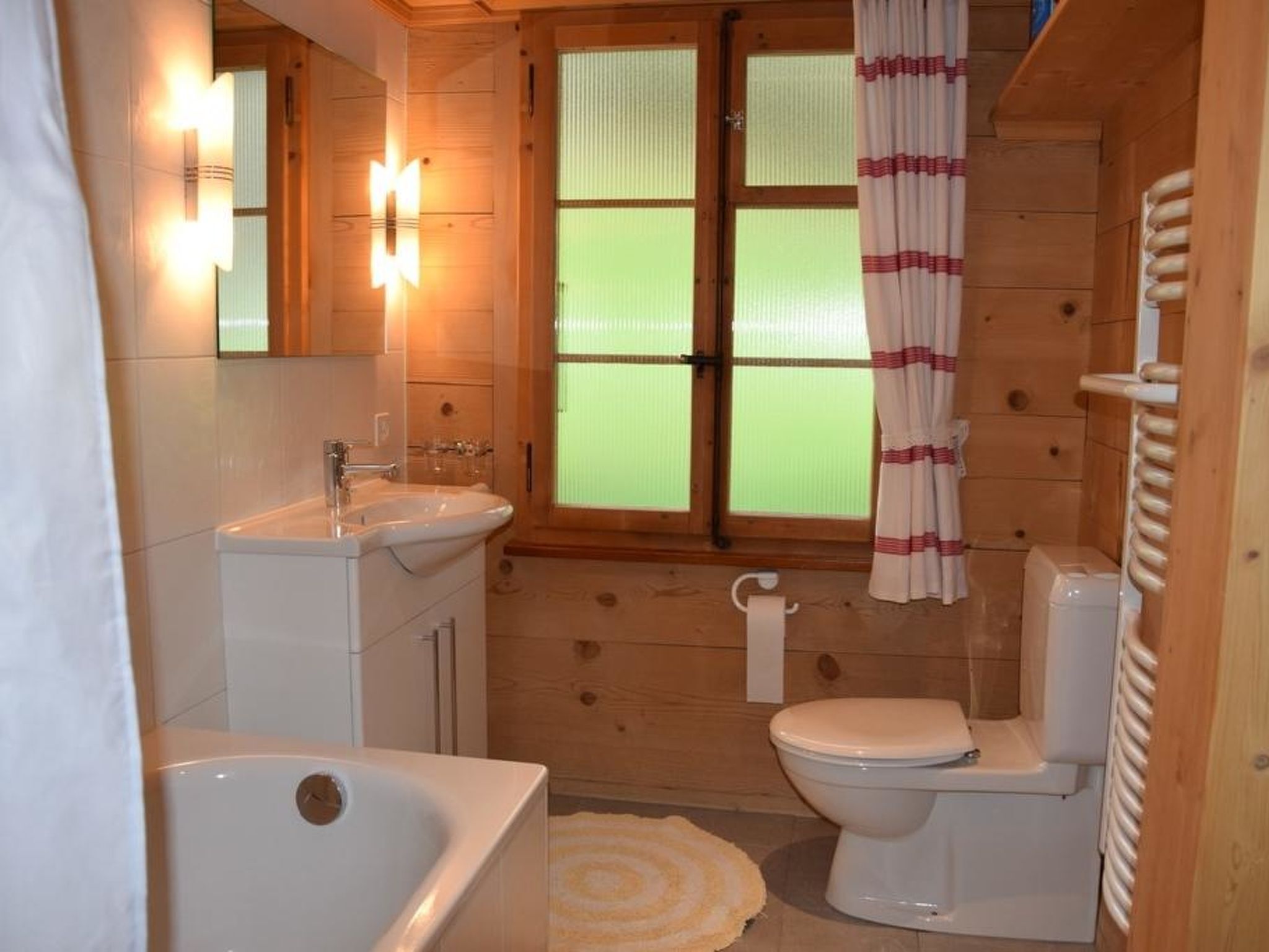 Un baño rústico en una cabaña de madera, con bañera, inodoro y lavamanos.