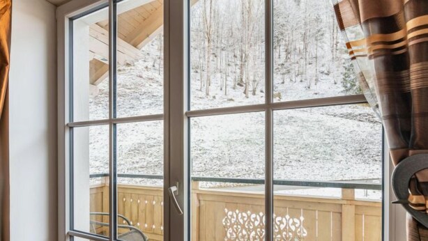 Une pièce dotée d’une grande fenêtre, d’une terrasse en bois et d’une chaise.