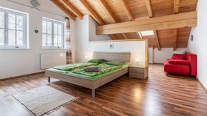Une chambre avec un plafond en bois, un lit avec une literie verte, une chaise rouge et un radiateur.