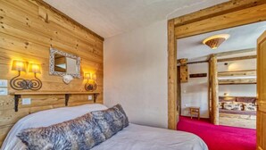 A wooden room with a bed, a mirror, and wall-mounted lamps. - Belleville Caron 1 - 1213 by Interhome (Les Menuires)