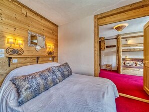 A wooden room with a bed, a mirror, and wall-mounted lamps. - Belleville Caron 1 - 1213 by Interhome (Les Menuires)