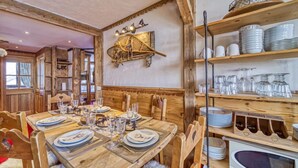 A wooden dining table set with plates, glasses, and cutlery, surrounded by chairs. - Belleville Caron 1 - 1213 by Interhome (Les Menuires)