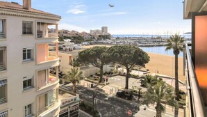 Vista costera con un puerto deportivo, un edificio con balcones y un cielo despejado.