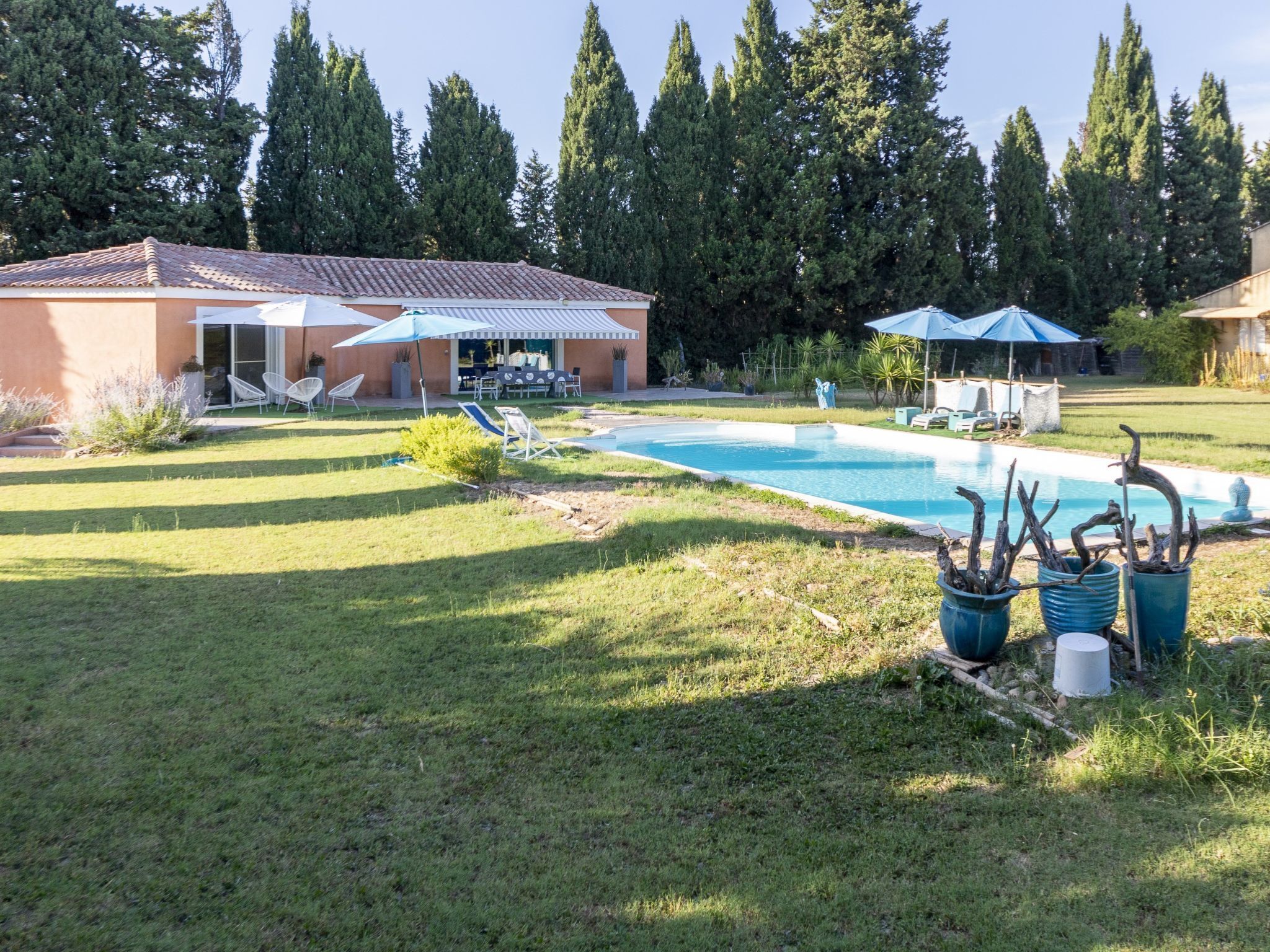 Un patio trasero con piscina, sillas de descanso y zona de estar.