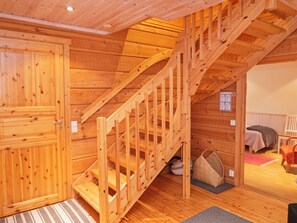 A wooden staircase leading to an upper level, a bed with a blanket, and a chair in a room with wooden walls and floors. - Suopursu by Interhome (Kuusamo)