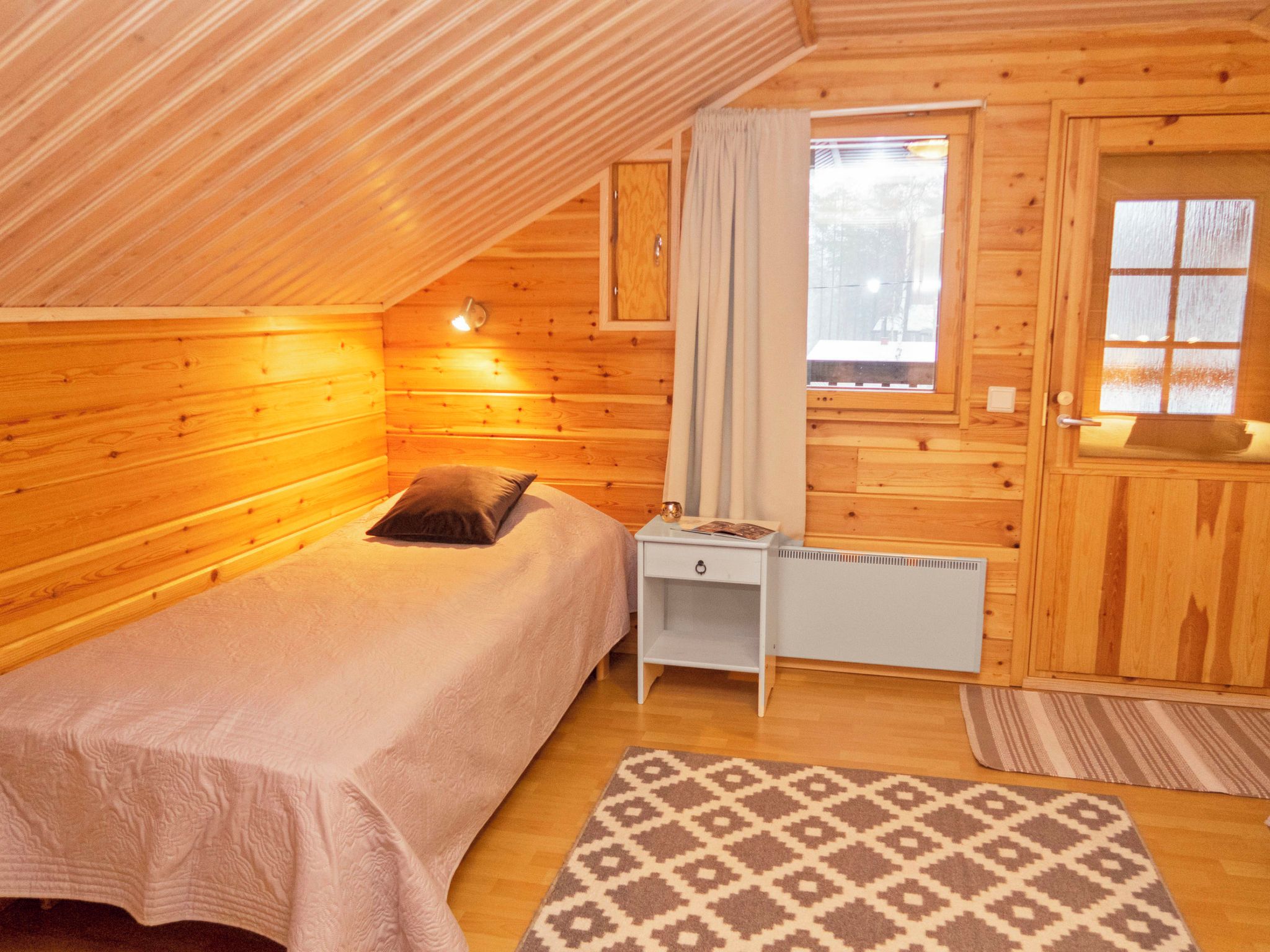Une pièce confortable avec un lit simple, un petit bureau, un radiateur et une fenêtre avec des rideaux.