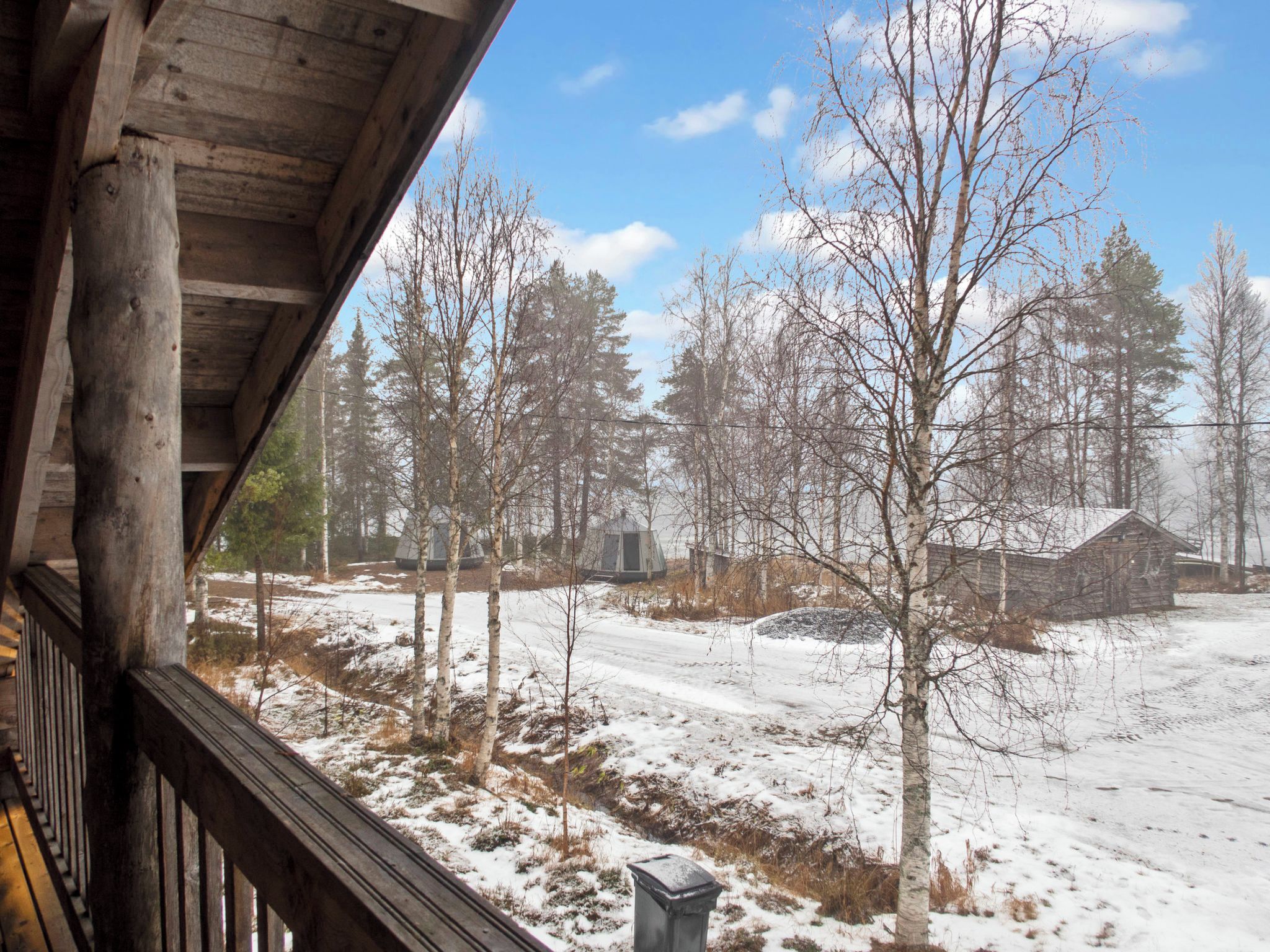 A wooden cabin with a view of a snowy landscape and trees.