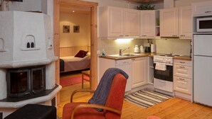 A compact kitchen with white cabinets, a stove, and a microwave. There is a small dining area with a chair and a table.