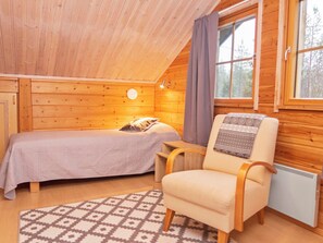 Acogedora habitación tipo cabaña de madera con una cama individual, una silla y un ventanal.