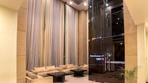 A lobby with a seating area, a glass door entrance, and a potted plant.