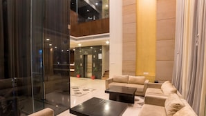 A modern lobby with a sofa area, a coffee table, and a glass partition.