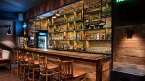 A bar area with wooden shelves stocked with various bottles and glasses, a Pepsi refrigerator, and a Heineken sign.